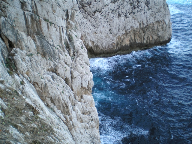 Il mare azzurrissimo si infrange sulla scogliera esplodendo con il suo rumore rimbombante in mille bianche goccioline.